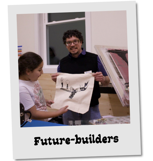 Photo styled as a tilted polaroid labeled "Future-builders." A smiling man and a child hold up a screen-printed cloth showing a moose or deer design, with printing equipment beside them.